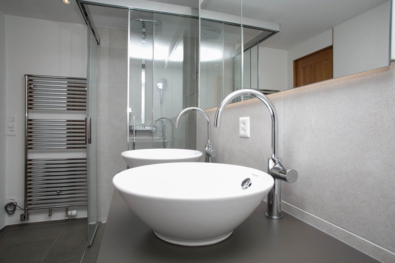 Badezimmer mit zwei Aufsatzwaschbecken und Duschwand